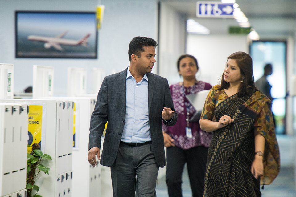 Three colleagues walking and talking in Boeing's India offices. 