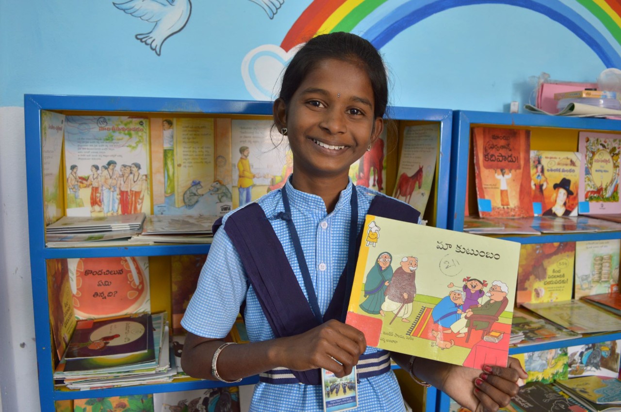 Child with big smile on their face holding a book